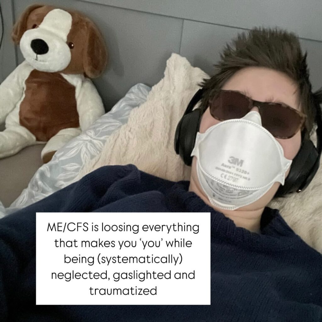 Mare is holding a sign that reads: ME/CFS is loosing everything that makes you ‘you’ while being (systematically) neglected, gaslighted and traumatized.
