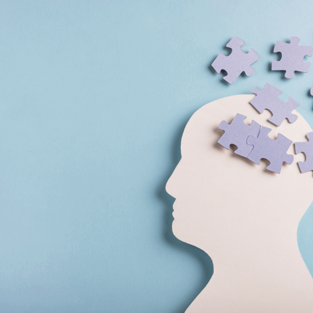 Silhouette of a human head on a blue background with puzzle pieces inside and floating away, symbolizing memory, thinking, or cognitive function.