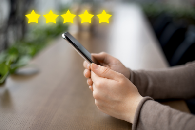 The image shows a person holding a smartphone. Above the phone, there are five yellow stars (five-star rating).